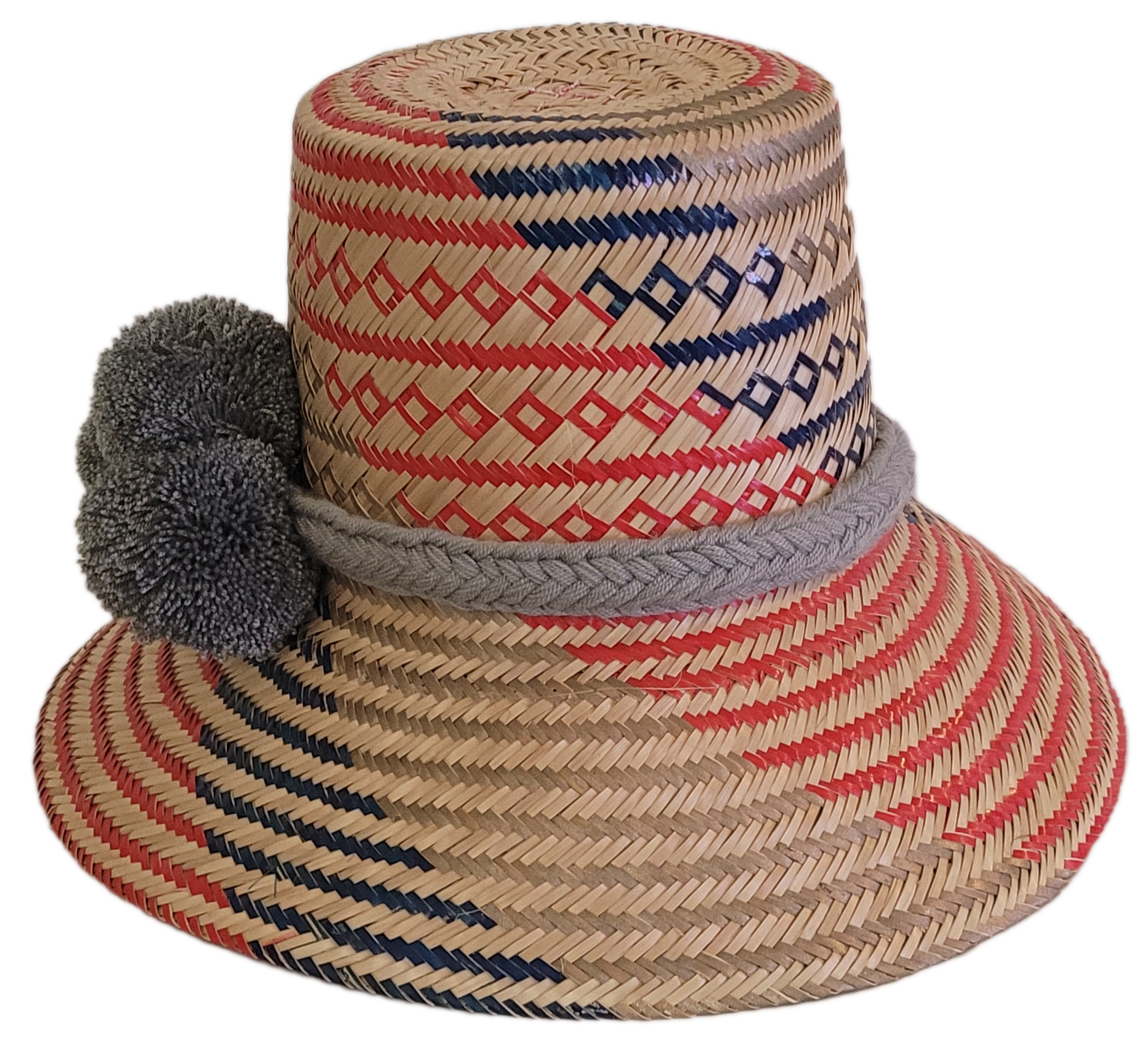 Bohemian-style handmade straw hat with geometric red and blue designs and gray pom-pom accent — artisan-crafted for sun protection and flair.