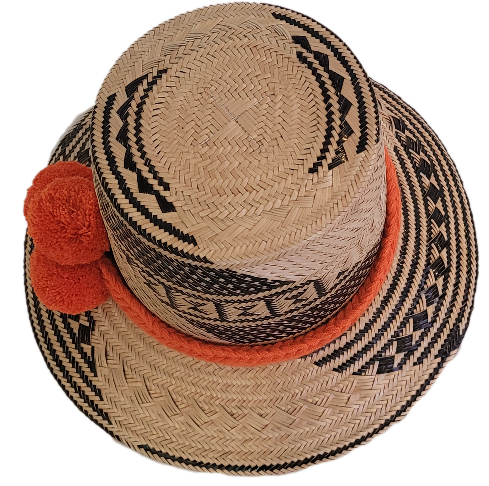Black and beige Wayuu straw hat with a bright orange braided band and pompoms — a colorful, handmade boho accessory full of artisan charm.