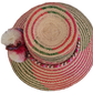 Artisan Wayuu straw hat with bold zigzag patterns and fluffy bohemian pom-poms in white, pink, and burgundy — lightweight and handmade fashion.