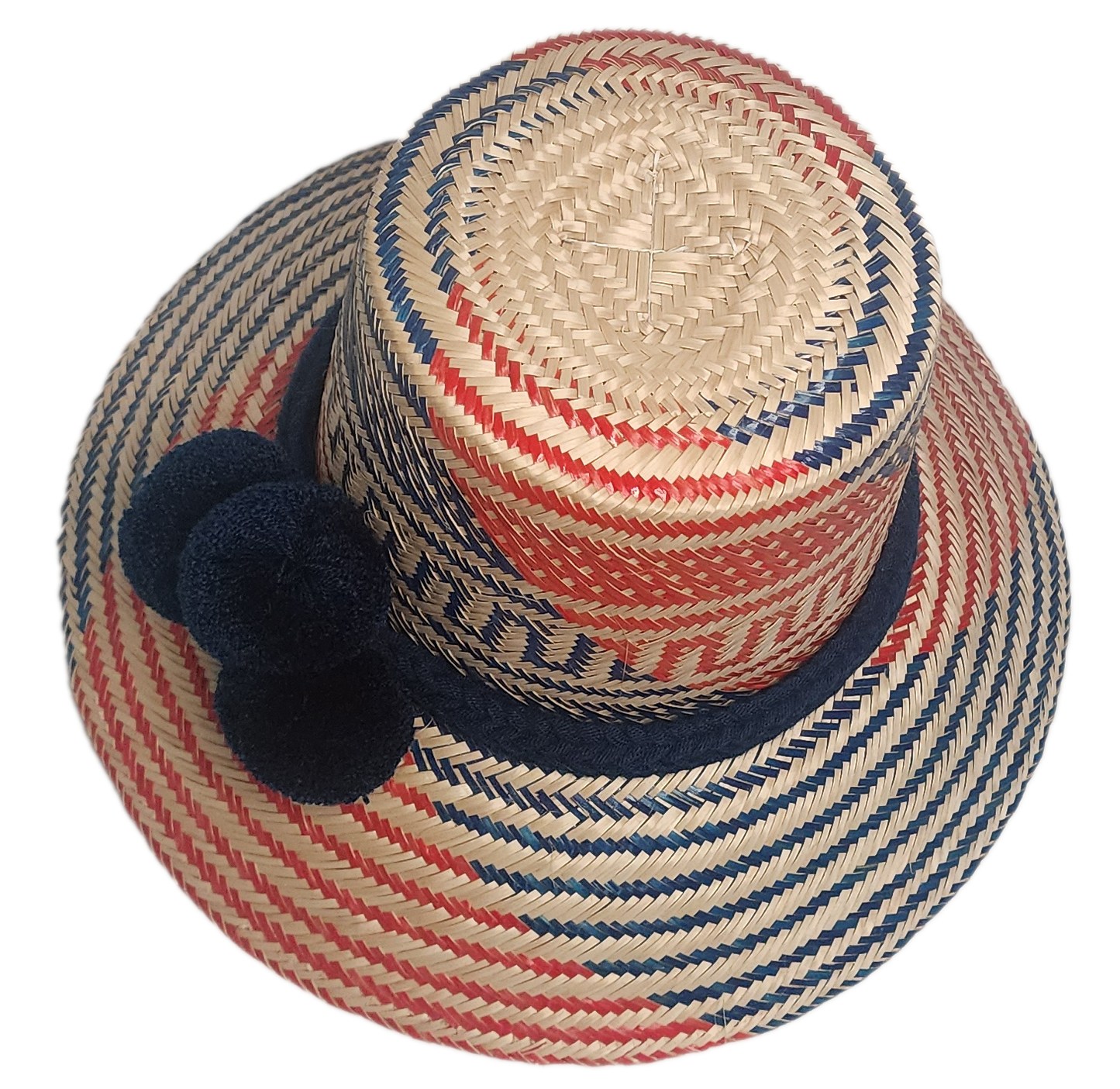 Boho-style Wayuu hat with red and blue weave, navy band, and matching pom-poms — crafted from Iraca palm for a bold, handmade summer look.