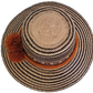 Artisan-crafted Wayuu straw hat with traditional patterns in black, finished with thick orange braided band and handmade pom-poms — perfect bohemian piece.