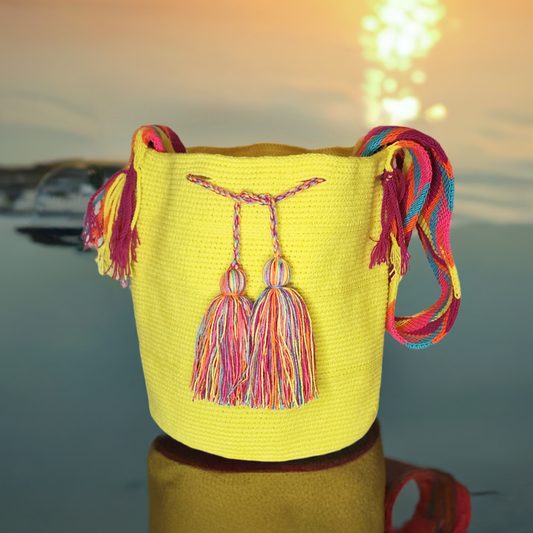 Handmade Wayuu crochet handbag in bright yellow with multicolor braided straps and rainbow oversized tassels, artisan-crafted.