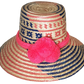 "Handmade Wuitusu Wayuu hat from Iraca palm fiber, adorned with colorful pompoms, showcasing adjustable and versatile styles.