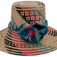 Keilani handmade Wayuu hat with natural, red, black, and green weave and blue pompoms


