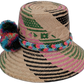 Artisan Wayuu hat Laila with natural palm base, pink and green patterns, and multicolor pompoms

