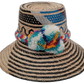 Lila handmade Wayuu straw hat with black, natural, and blue weave and multicolor pompoms

