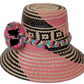 Boho straw hat Lilah featuring artisan pink and black weave with multicolor pompoms


