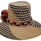 Boho Wayuu hat Margo featuring natural straw base with earth-tone accents and pompoms

