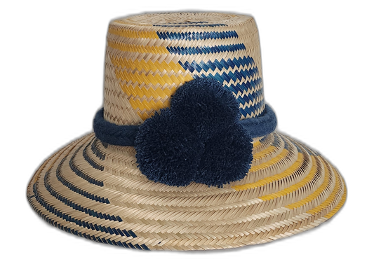 Handmade Wayuu straw hat in yellow and navy with bold navy pompoms.Maria handmade Wayuu hat with yellow and navy diagonal weave and blue pompoms in Bohemian colors