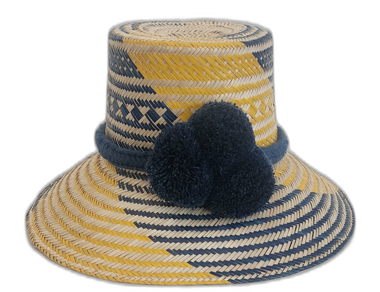 Handmade bohemian straw hat in navy and yellow with pompoms, crafted by Wayuu artisans.Boho straw hat with bold blue pompom trio and golden zigzag pattern

