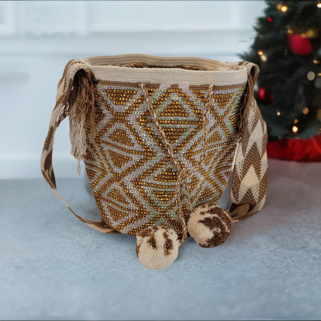 Handmade Wayuu crochet bag in gold and cream with diamond patterns and pom-poms.