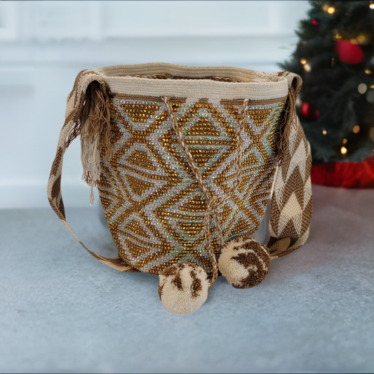 Handmade Wayuu crochet bag in gold and cream with diamond patterns and pom-poms.
