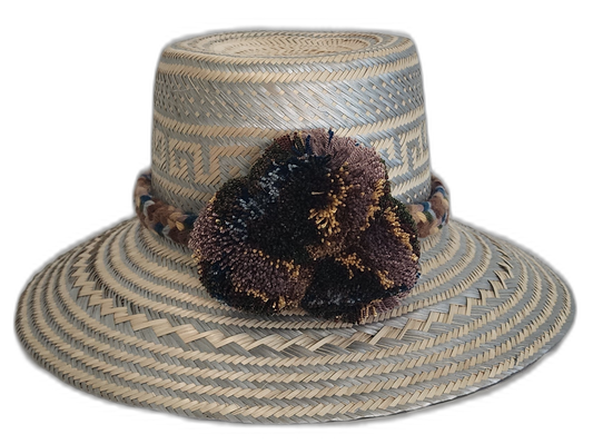 Handmade Wayuu straw hat in earth tones with soft pompom accents

