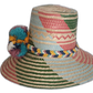 Boho chick Wayuu straw hat featuring pink, green, blue, and zigzag patterns with colorful pompom trim.

