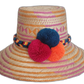 Handmade Wayuu straw hat with pink, orange, and natural weave featuring blue, fuchsia, and orange pompoms.