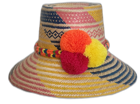 Handmade Wayuu boho straw hat with pink, yellow, and blue woven pattern and bold yellow, fuchsia, and orange pompoms.