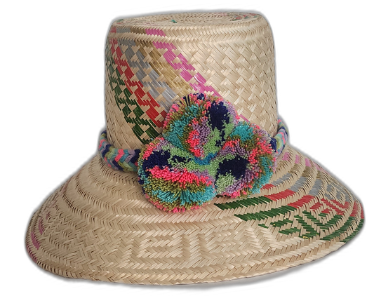 Handmade Wayuu straw hat with rainbow-colored weaving and vivid multicolor pompoms, crafted from Iraca palm.