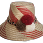 Handmade Wayuu straw hat featuring bold red patterns, with decorative white, brown, and red pompoms.