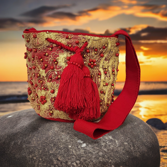 Handmade Wayuu bag in red with gold embroidery, beads, and large tassels.