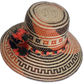 Artisan boho straw hat in natural straw with red and black patterns and colorful pompoms.

Wayuu hat with bold woven design and handcrafted green and red pompoms.