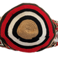 Vegan handmade Wayuu bag, black crochet design with red and tan accents, crossbody strap, and artisan tassels, perfect for boho chic fashion.