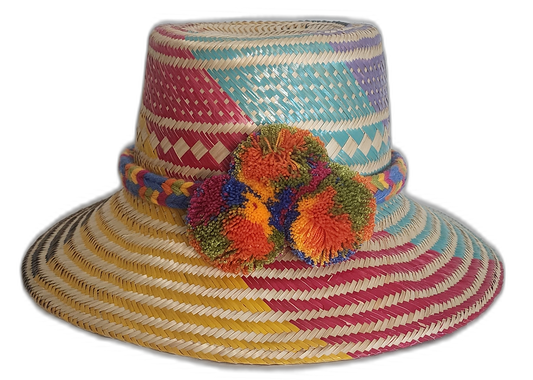 Handmade Wayuu straw hat with bold pink, blue, yellow, and purple weave and colorful orange pompoms.