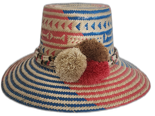 Handmade Wayuu straw hat with red and blue weave and ivory, brown, and red pompoms.