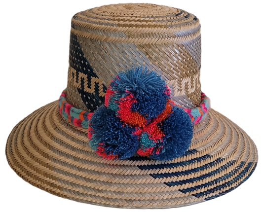 Handmade Wayuu straw hat with blue, coral, and teal pompoms.
