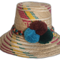 Handmade Wayuu straw hat with red, yellow, and green weaving, accented by large pompoms in brown, teal, and green.