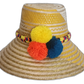 Handmade Wayuu straw hat with yellow stripes and yellow, blue, and orange pompoms.Bohemian straw sun hat handcrafted by Wayuu artisans in yellow tones

